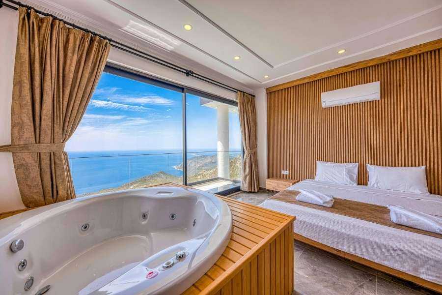 Chambre d'hôtel de luxe avec jacuzzi intérieur donnant sur la mer et la montagne, pour un séjour spa d'hôtel inoubliable.